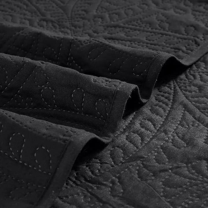 Close-up of a textured black quilt with visible stitching details.
