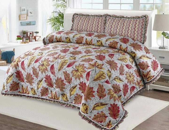 Bed with a colorful leaf-patterned comforter and pillows in a bright bedroom.