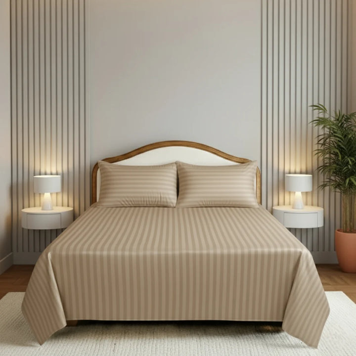 Beige striped bedding set on a bed in a bedroom with lamps and a plant.
