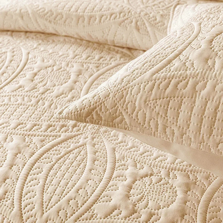 Close-up of a textured beige quilt with a pillow on top