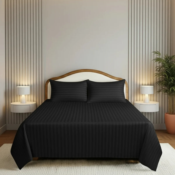 Black bedspread set on a bed in a bedroom with two lamps and a plant.