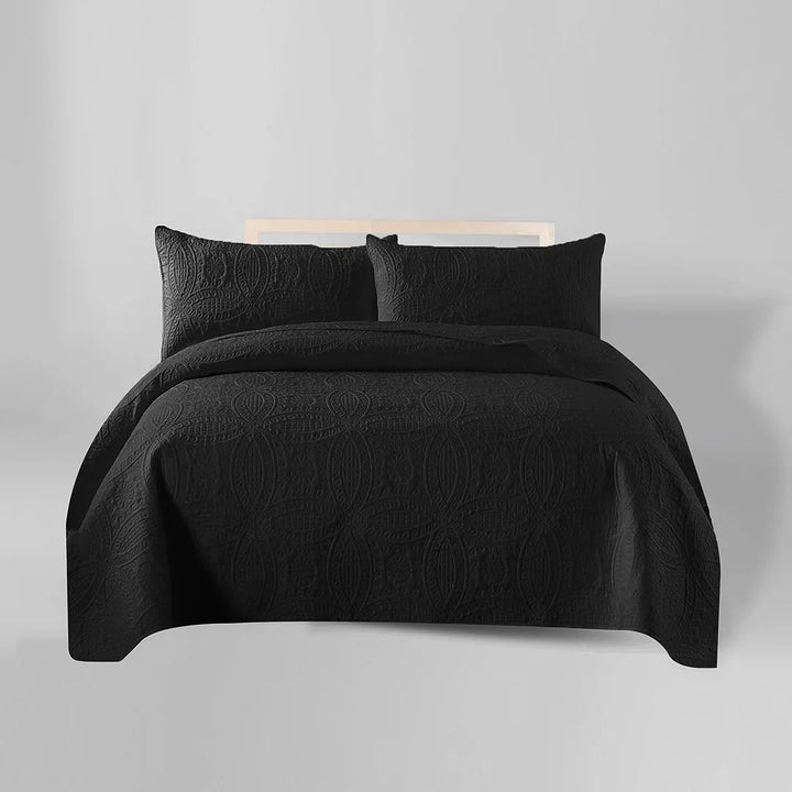 Black bedding set on a bed with a plain background
