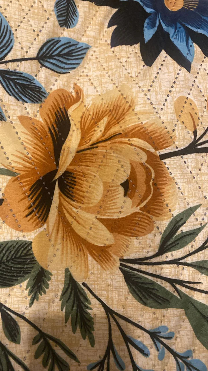 Close-up of a floral pattern with orange flowers, green leaves, and blue accents on a textured beige background.