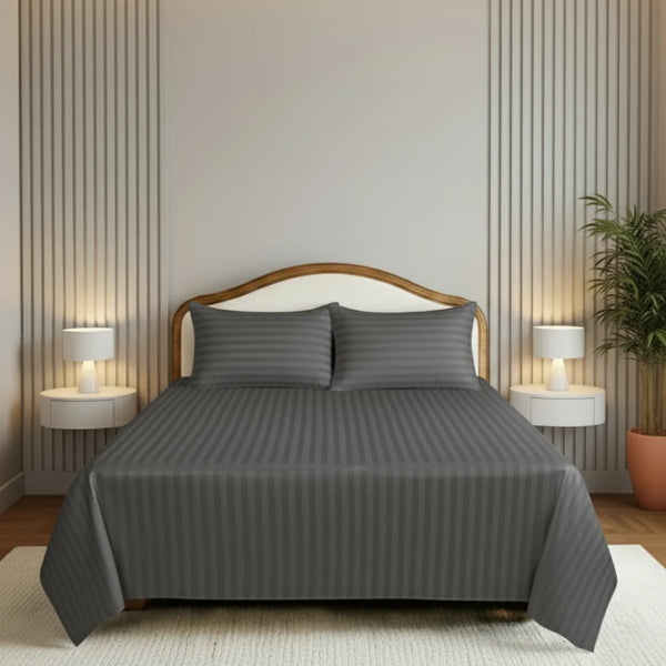 Gray bedding set on a bed in a bedroom with nightstands and lamps.