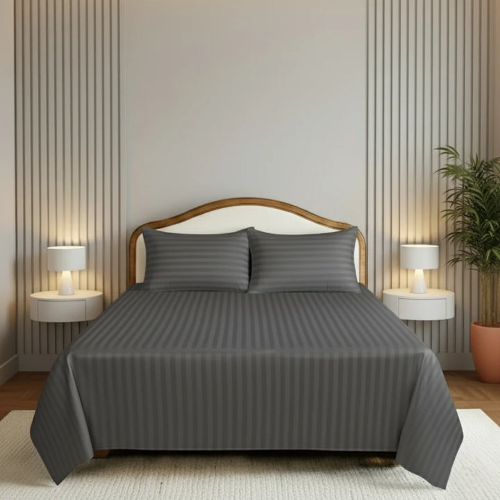 Gray bedding set on a bed in a bedroom with nightstands and lamps.