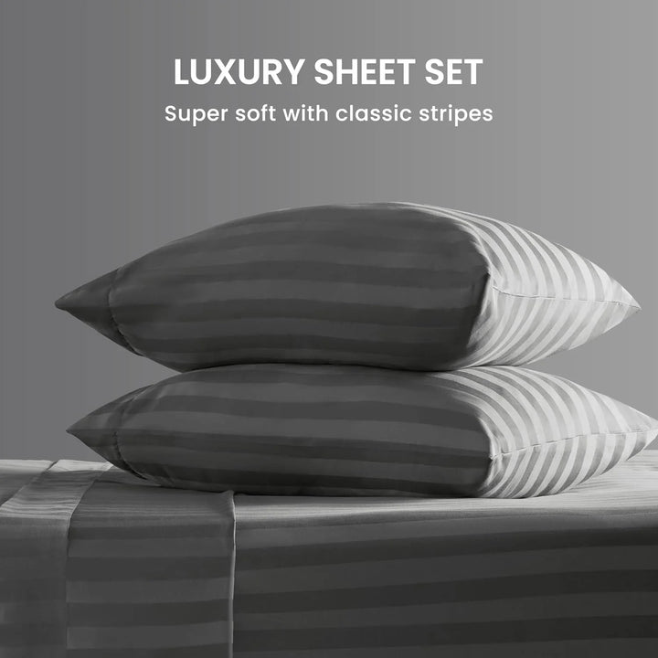Stack of striped pillows and sheets on a bed with a gray background