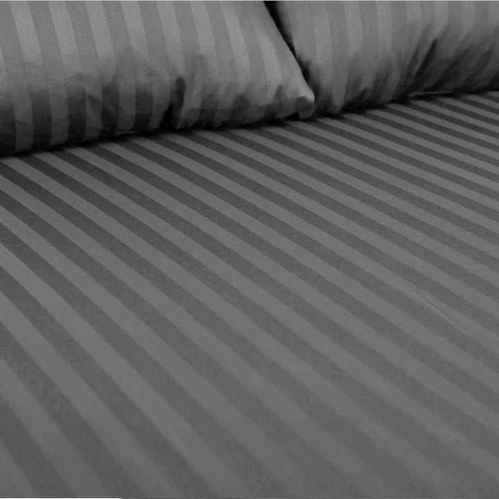 Gray striped bed sheets on a bed with pillows.
