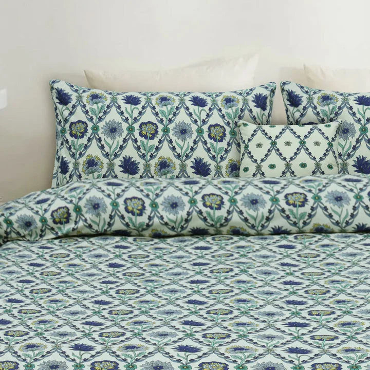 Floral patterned bedspread and pillows on a bed with a white background
