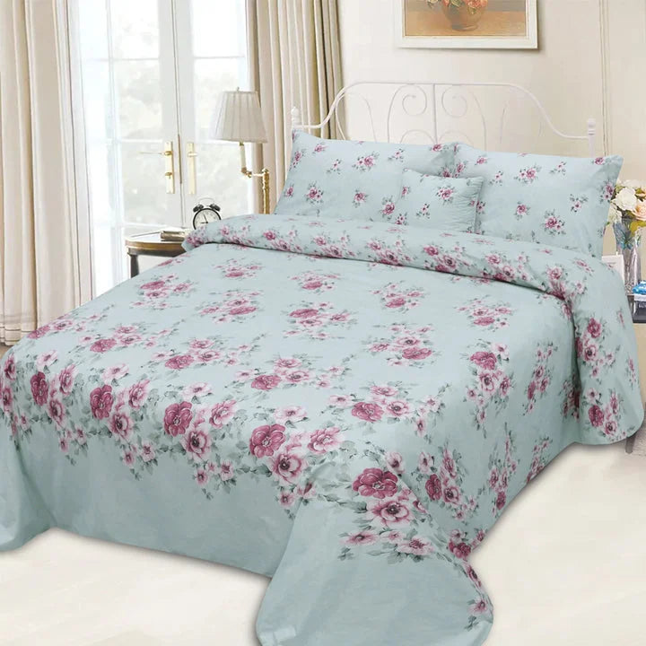 Floral bedding set on a bed in a bedroom with curtains and a lamp.