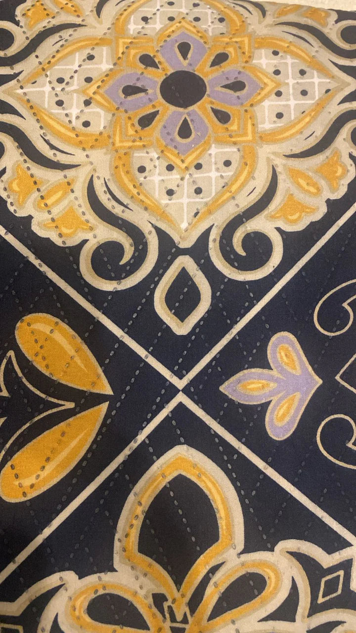 Close-up of decorative fabric with intricate patterns in gold, purple, and black.