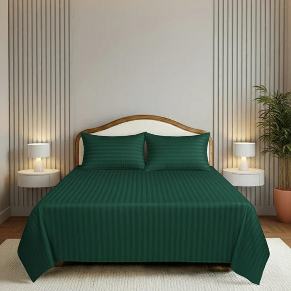 Green striped bedspread set on a bed in a bedroom with lamps and a plant.