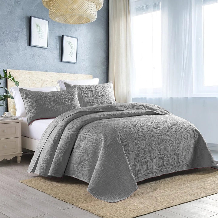 grey quilted bedspread set on bed with amazing background 