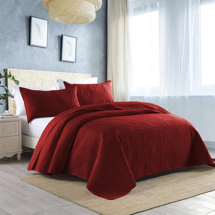maroon quilted bedspread set on bed with amazing background