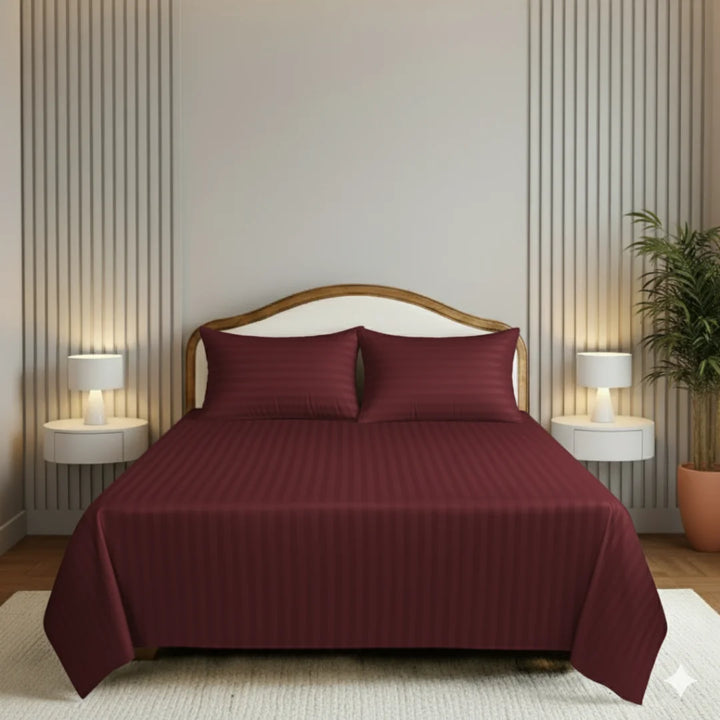 Bed with burgundy bedding in a bedroom setting with lamps and decor.