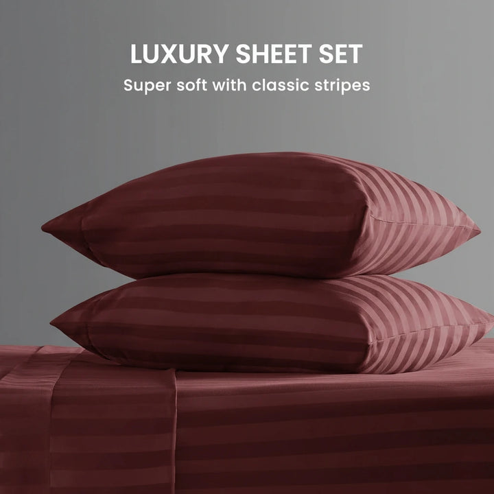 Stack of burgundy striped pillows and sheets on a gray background with text 'Luxury Sheet Set'.