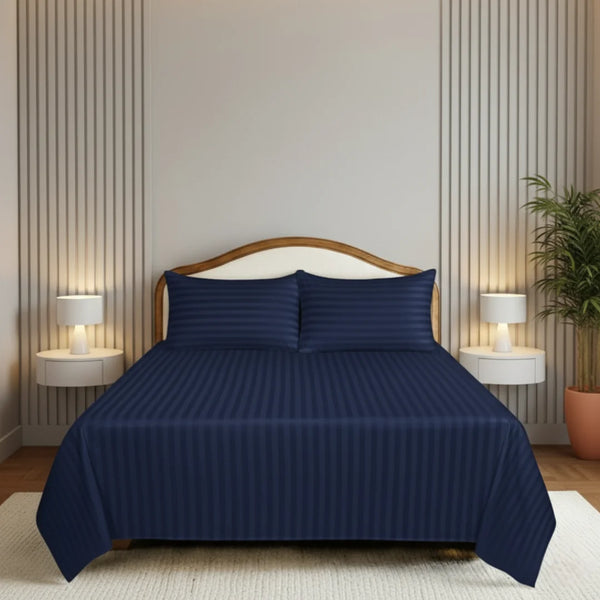 Navy blue bedspread set on a bed in a bedroom with striped walls and lamps.