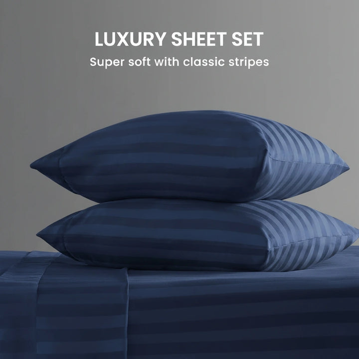 Navy blue striped pillows and sheet set on a gray background with text 'Luxury Sheet Set' and 'Super soft with classic stripes'.