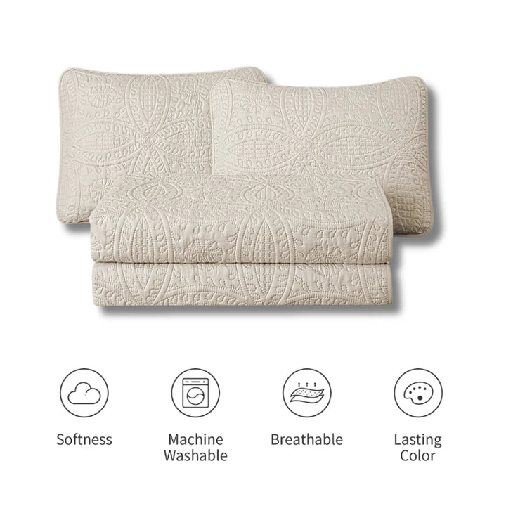 Beige quilted coverlet with patterns on a white background, featuring icons for softness, machine washability, breathability, and lasting color.