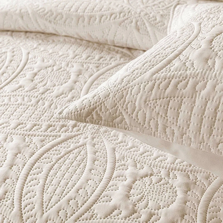 Close-up of a textured beige quilt with a pillow on top