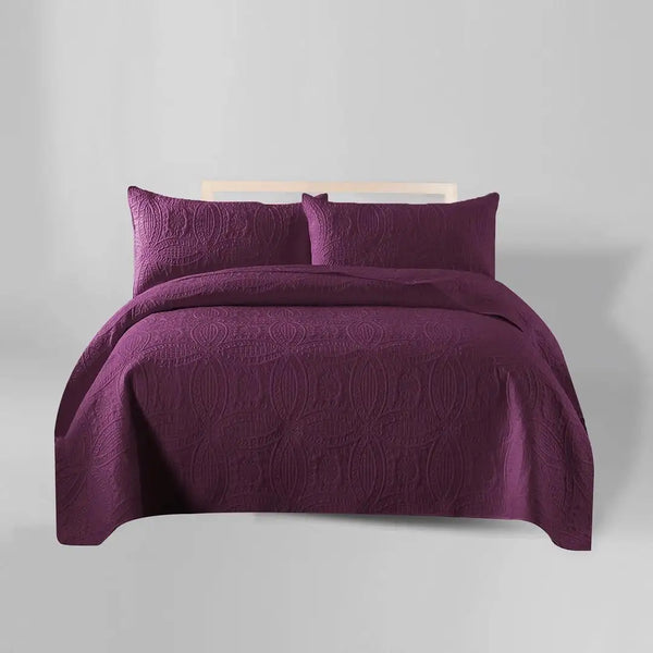 Purple bedspread set with matching pillows on a gray background