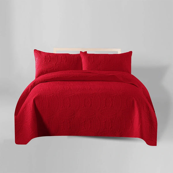 Red quilt and pillow set on a bed against a gray background