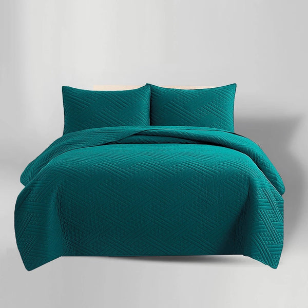 Teal quilt set with two matching pillows on a light gray background